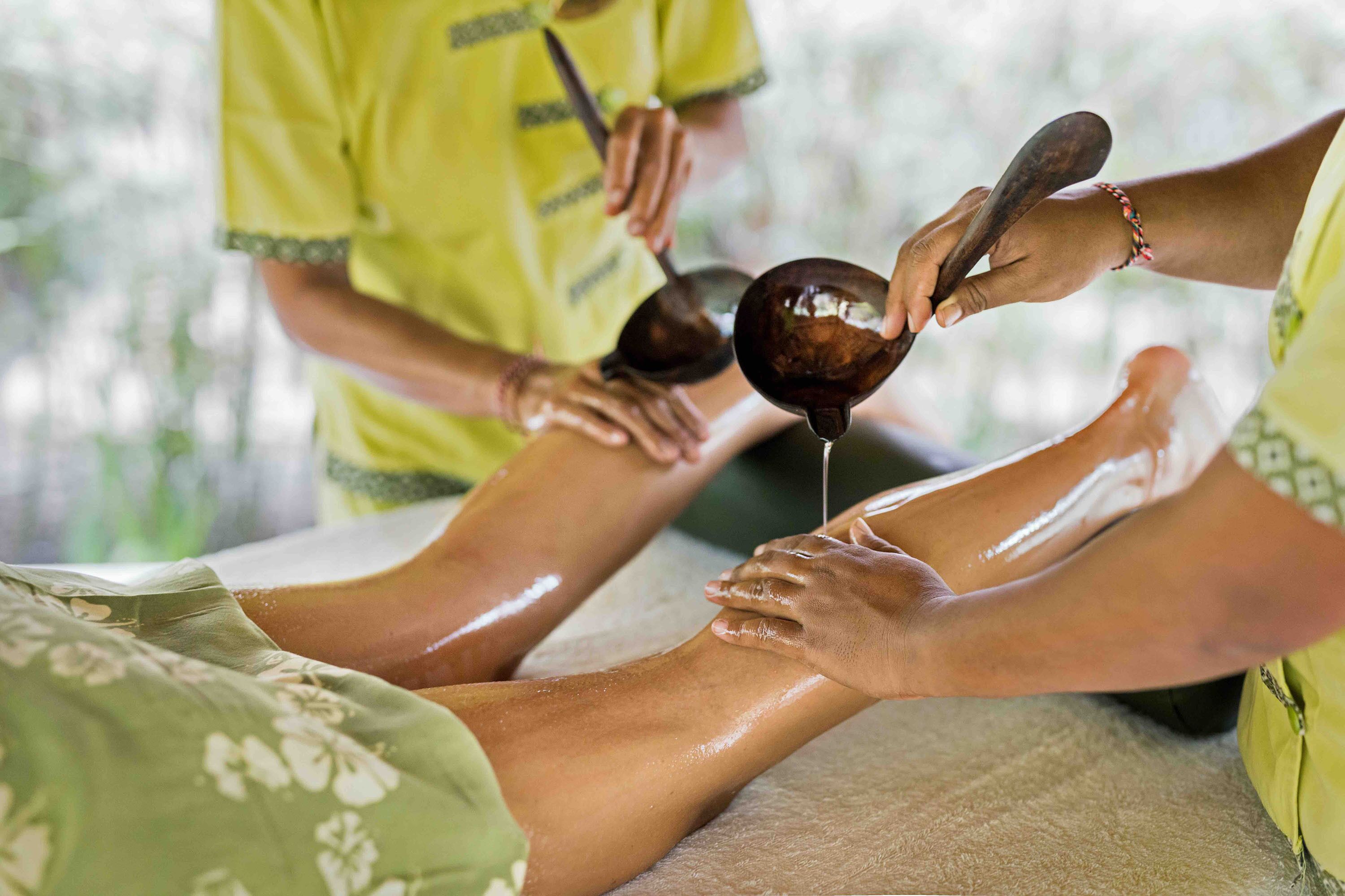 A person receiving a foot massage with a dark liquid being applied.