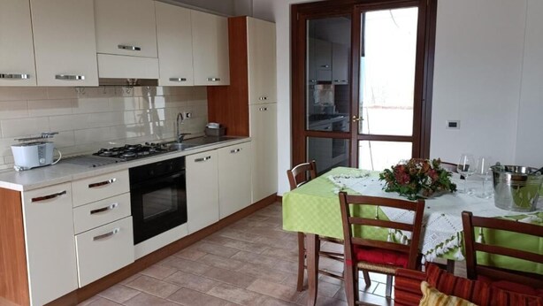 A kitchen with white cabinets, a stove, and a dining area with a table set for two.