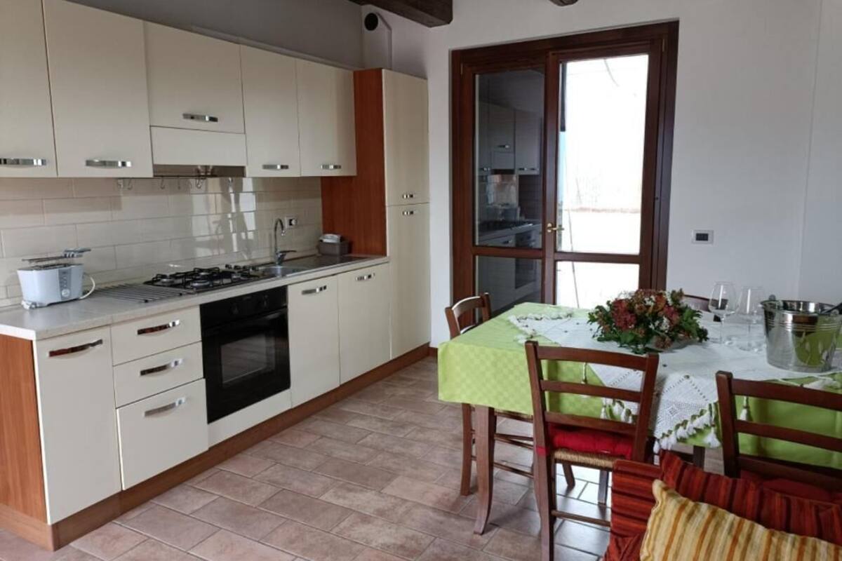 A kitchen with white cabinets, a stove, and a dining area with a table set for two.