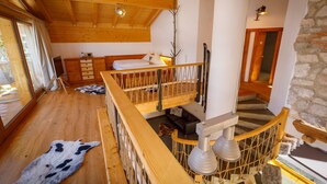 A wooden interior with a staircase, a bed, a wooden dresser, and a fur rug. - Alpenloft 1.0 (Mittenwald)