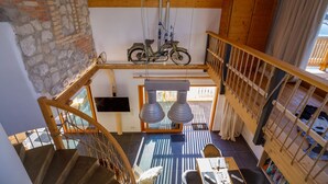 A multi-level wooden interior with a staircase, a bicycle mounted on the wall, and a hanging light fixture. - Alpenloft 1.0 (Mittenwald)