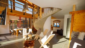 A spacious living area with a high ceiling, a wooden staircase, and a ski rack. - Alpenloft 1.0 (Mittenwald)