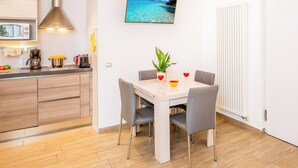 Een moderne keuken met een magnetron, koffiezetapparaat en een eettafel met stoelen.
