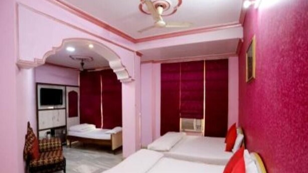 A room with two beds, a television, and a chair. - Hotel Shri Ram International (Varanasi)