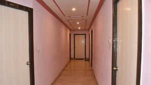 A corridor with a tiled floor, wooden doors, and a ceiling with recessed lighting. - Hotel Shri Ram International (Varanasi)
