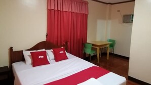 A hotel room with a wooden bed, red and white bedding, a desk, and a chair. - OYO 879  Lauriens Budget Hotel 2 (Tagaytay)