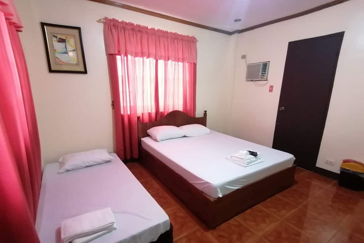 A room with two beds, a wooden headboard, a framed picture on the wall, and a door with a black frame.