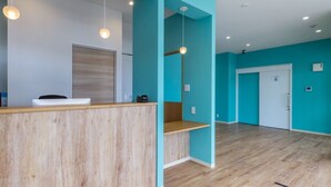 A reception area with a wooden counter, teal walls, and a wooden floor. - Mr.KINJO LINK in Kugai Miyakojima (Miyakojima)