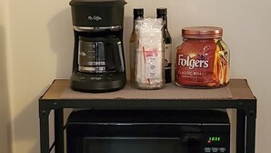 A kitchen counter with a microwave, coffee maker, and condiments.