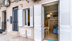 A residential building with a front door, a staircase, and a visible interior with a dining area and a blue sofa. - GuestHost - Cozy 50 sqm apartment, able to accommodate up to 3 people, located on the ground floor of a building facing the beach. The property is located in Giardini Naxos, a wonderful seaside area 1.8 km from the pretty village of Schisò and just 2 km (Giardini Naxos)