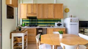 A compact kitchen with wooden cabinets, a microwave, a stove, and a dining table with chairs. - GuestHost - Cozy 50 sqm apartment, able to accommodate up to 3 people, located on the ground floor of a building facing the beach. The property is located in Giardini Naxos, a wonderful seaside area 1.8 km from the pretty village of Schisò and just 2 km (Giardini Naxos)