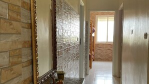 A hallway with a tiled floor, a decorative console table with a mirror, and a view into another room. - Grand Duplexe Mer et Piscine in Tangier (طنجة)