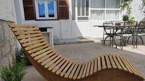 A wooden lounge chair with a curved design, positioned on a concrete surface. - Stunning 2-bed House in Jezera With Sea Views (Tisno)