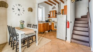 Eine Küche mit Holzausstattung, einem weißen Kühlschrank und einem Essbereich mit Tisch und Stühlen.