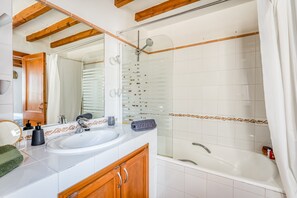 Een badkamer met een wastafel, spiegel, douche en bad.