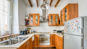 Eine Küche mit Holzschränken, einer Edelstahl-Spüle, einem Einbauofen und einem Kühlschrank mit Magneten.