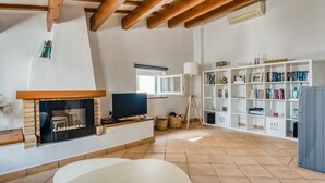 Ein Wohnzimmer mit Kamin, Fernseher, Bücherregal und Fenster.