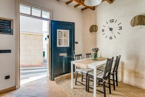 A dining area with a white table, dark chairs, a woven rug, and a wall clock. - Casa Agnès in the Historic Center with Air Conditioning and Wi-Fi (Mahón)