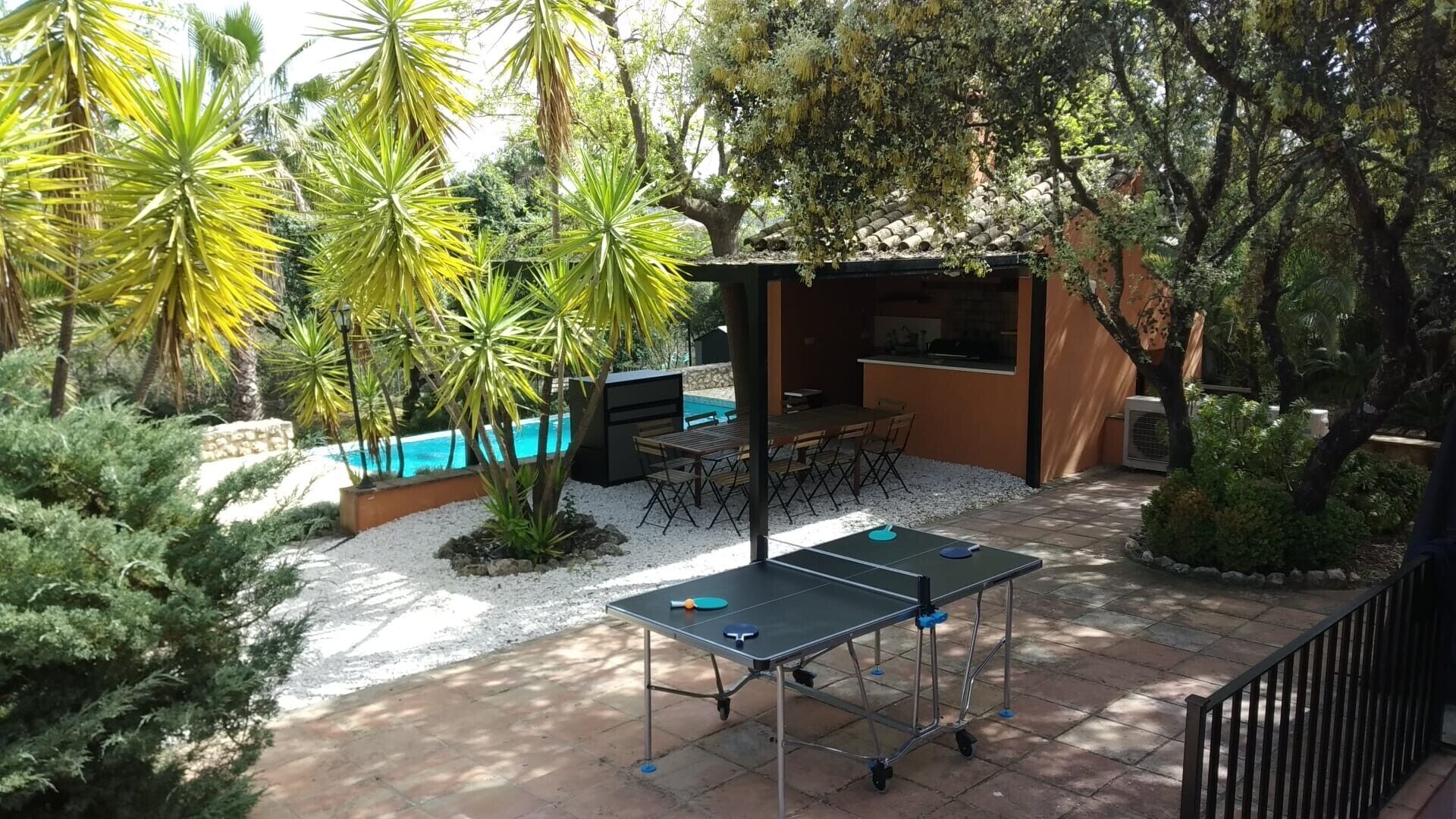 An outdoor patio with a ping pong table, a barbecue area, and a pool.