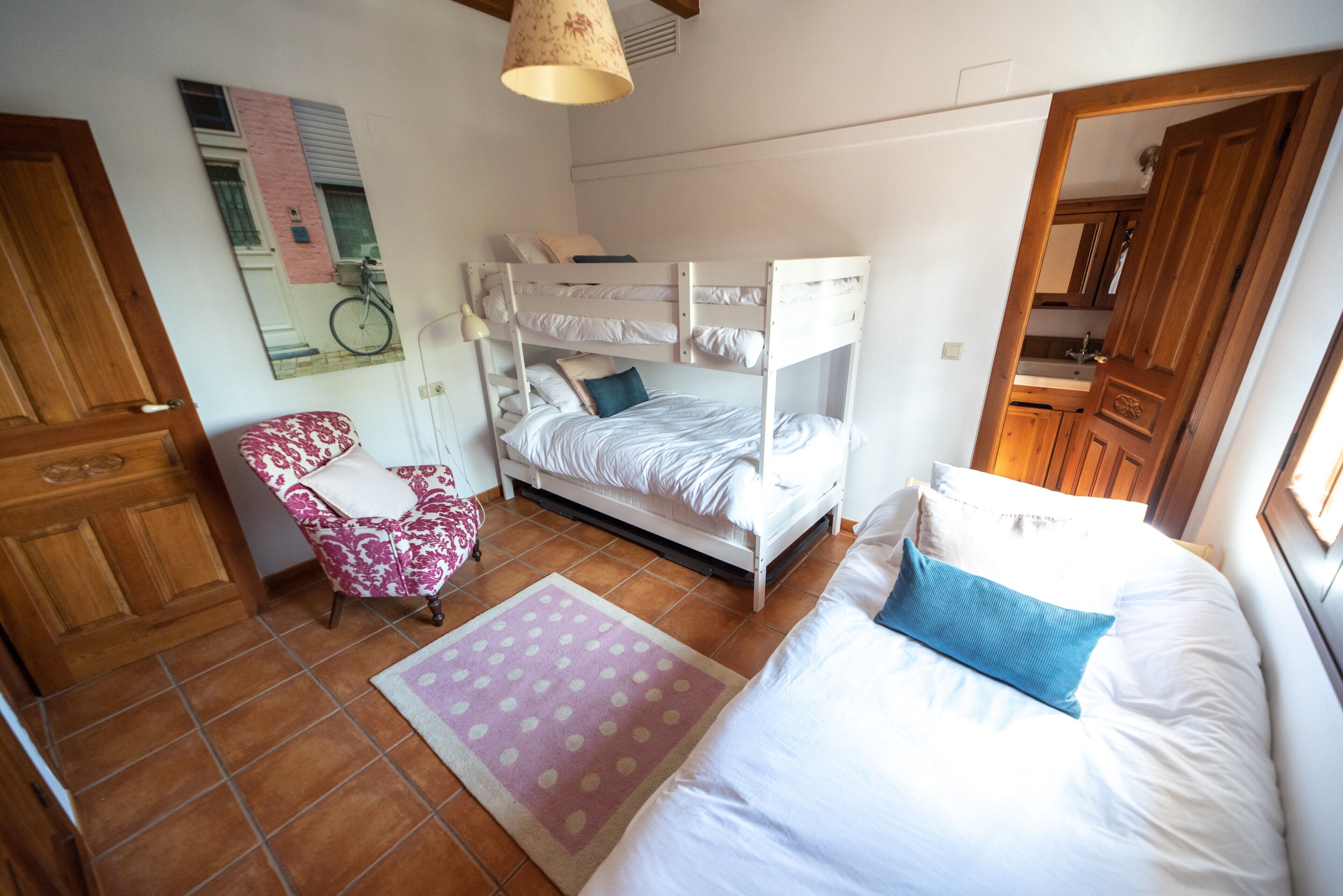 Una habitación con una cama litera, una silla, un tapete y un espejo en la pared.