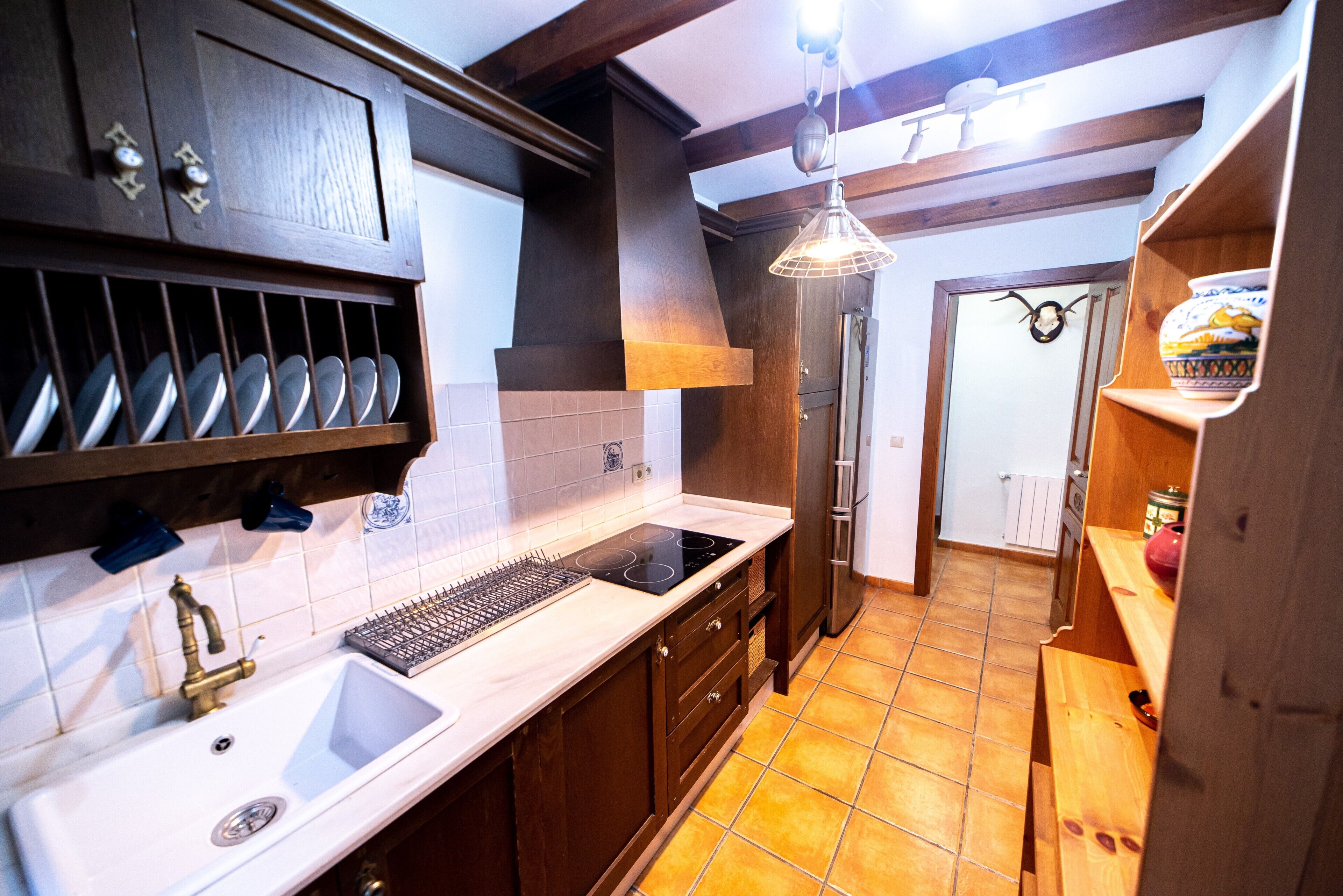 A kitchen with a sink, stove, and wooden cabinets.