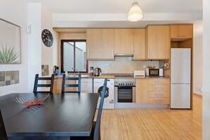 A modern kitchen with wooden cabinets, a built-in oven, a microwave, and a refrigerator. - Casa 'Tazacorte' with Sea Views, Shared Pool and Wi-Fi (Tazacorte)