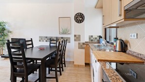 Una cucina moderna con zona pranzo, un orologio appeso al muro e una pianta in vaso.