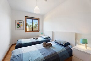 A bedroom with two beds, a window, a painting, a bedside table with a lamp, and a nightstand. - Casa 'Tazacorte' with Sea Views, Shared Pool and Wi-Fi (Tazacorte)