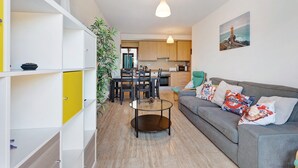 Un soggiorno moderno con un divano grigio, un tavolino in vetro e una zona pranzo con sedie in legno.