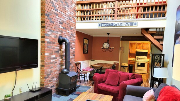 Una sala de estar con televisión, chimenea, sofá y comedor con mesa y sillas.