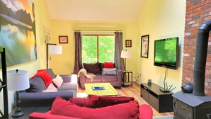 Una sala de estar con un sofá, una mesa de centro, un televisor, una chimenea y un cuadro en la pared.