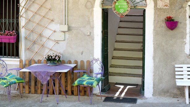Un espace extérieur aménagé dans un style rustique, avec une table, des chaises et un panneau décoratif.