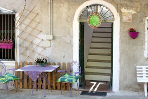 Un espace extérieur aménagé dans un style rustique, avec une table, des chaises et un panneau décoratif.