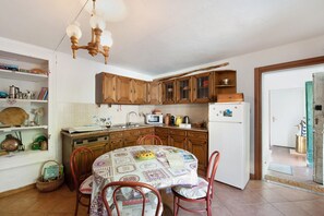 Une cuisine dotée de meubles en bois, d’un four à micro-ondes, d’un réfrigérateur, d’une table à manger avec des chaises et d’un lustre.