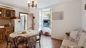 Une cuisine équipée d’une table à manger, de chaises, d’un réfrigérateur et d’un lustre.