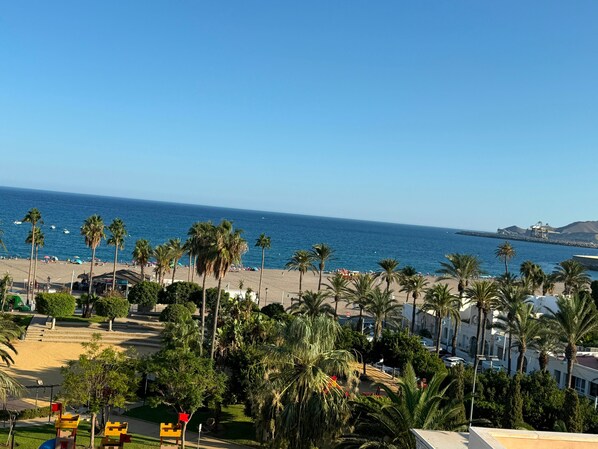 A beach with palm trees, a clear sky, and a distant ship.