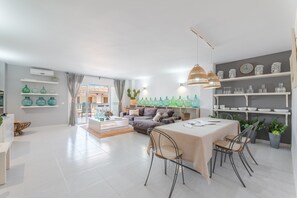 A modern living room with a dining area, a sofa set, and decorative items on shelves.