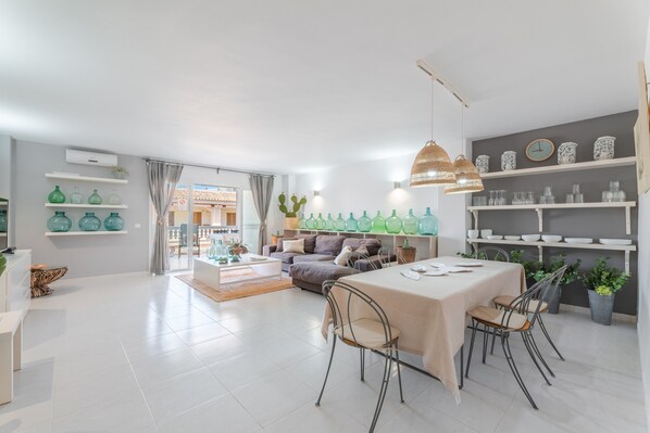 A modern living room with a dining area, a sofa set, and decorative items on shelves.
