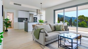 Un espacio habitable moderno con sofá, mesa de centro y vistas a las montañas a través de amplios ventanales.