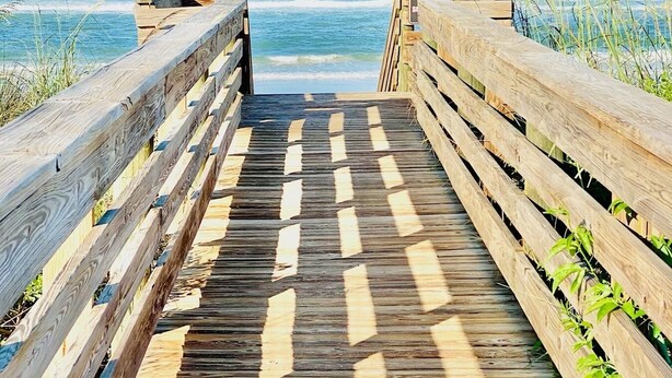 A wooden boardwalk leading to a beach with clear blue water and a clear sky. - Oceanfront Condo, Private Balcony (Palm Coast)