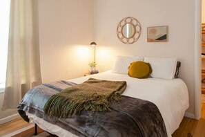 Un dormitorio con una cama, una lámpara de noche, un espejo y un cuadro en la pared.