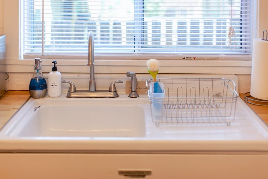 A kitchen sink with a faucet, soap dispenser, and a dish rack.