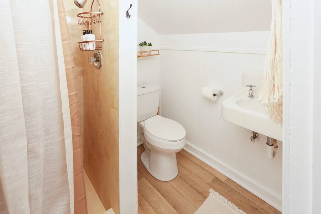 A bathroom with a toilet, sink, and shower area.