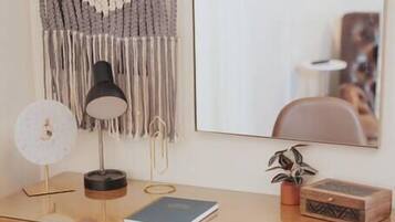 Een houten bureau met een lamp, een spiegel en een plant.