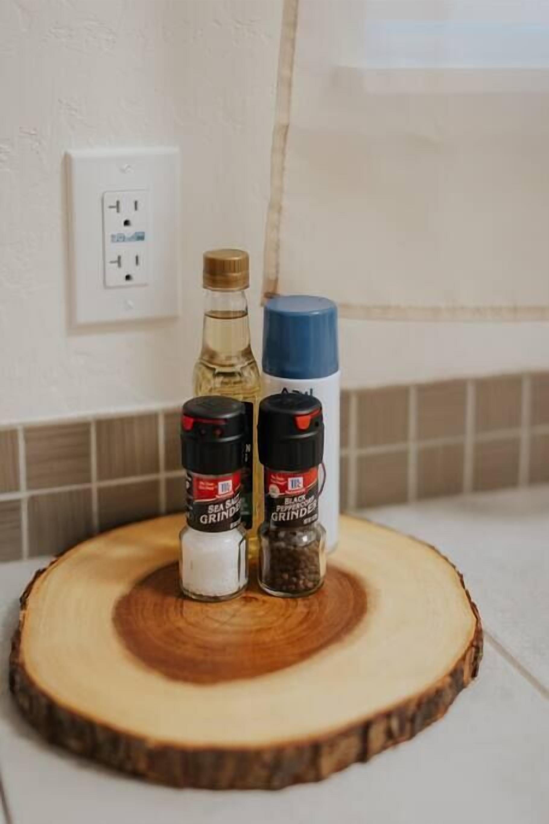 Una encimera de cocina con una tabla de cortar de madera, un salero, un pimentero y una botella de aceite.