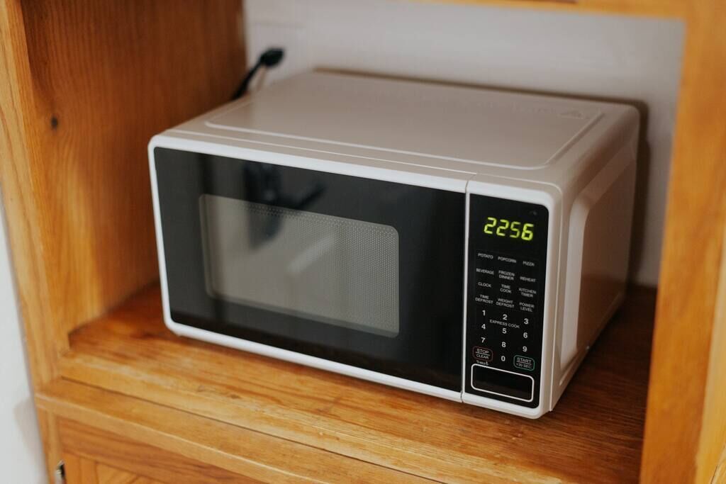 Un horno microondas sobre un estante de madera.