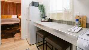 Una cocina compacta con refrigerador, una encimera y una ventana con persianas.