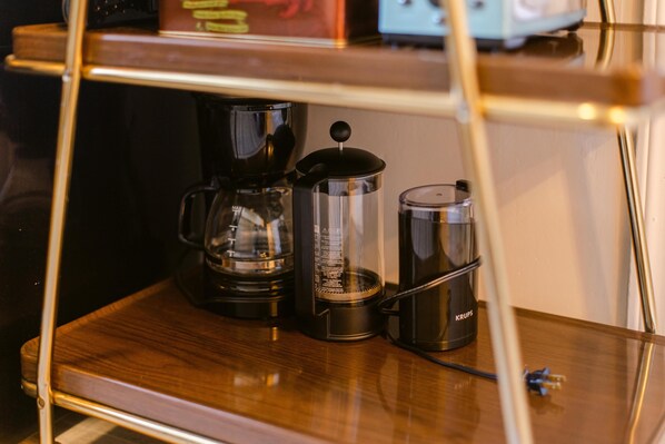A coffee maker on a wooden table with a glass carafe and a Krups coffee pot.