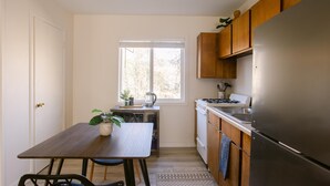 Una cocina funcional con mesa, sillas, refrigerador y armarios de madera.
