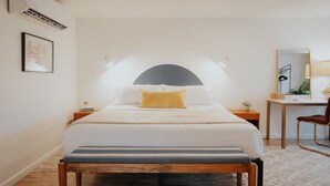 A neatly arranged hotel room with a bed, a desk, a chair, and a small table. - Located in a scenic area perfect for travelers along I-5. You are right by the Rogue River, offering stunning views and tranquility, yet conveniently positioned for easy travel access. (Gold Hill)